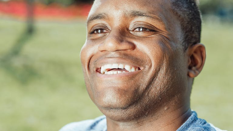 Close-up of a smiling man outdoors, showcasing happiness and positivity.